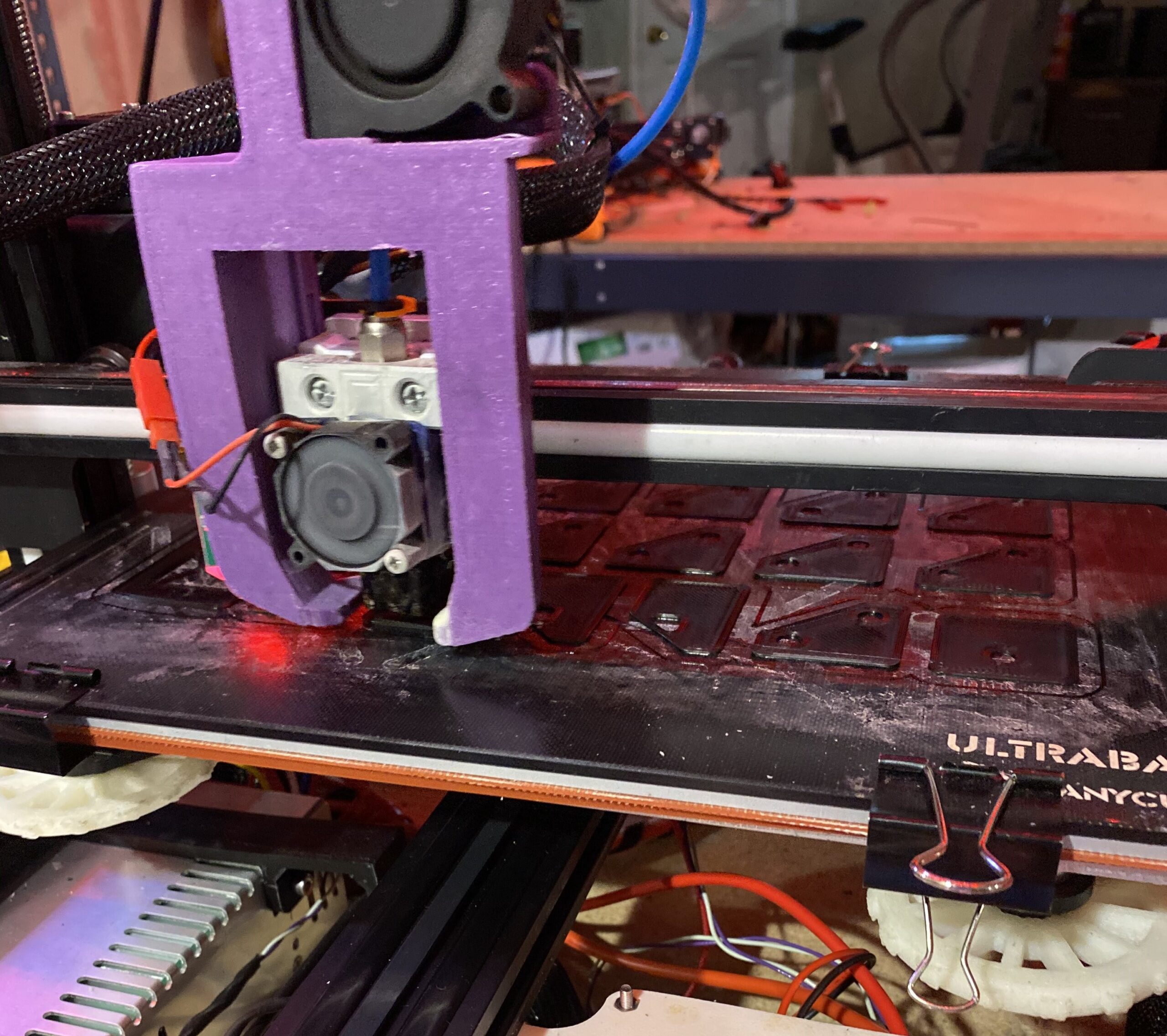 FDM print head over a build plate holding several flat printed components